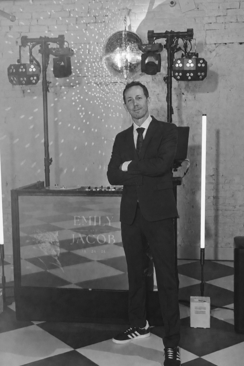 Matt in a suit, arms crossed, standing in front of his DJ booth